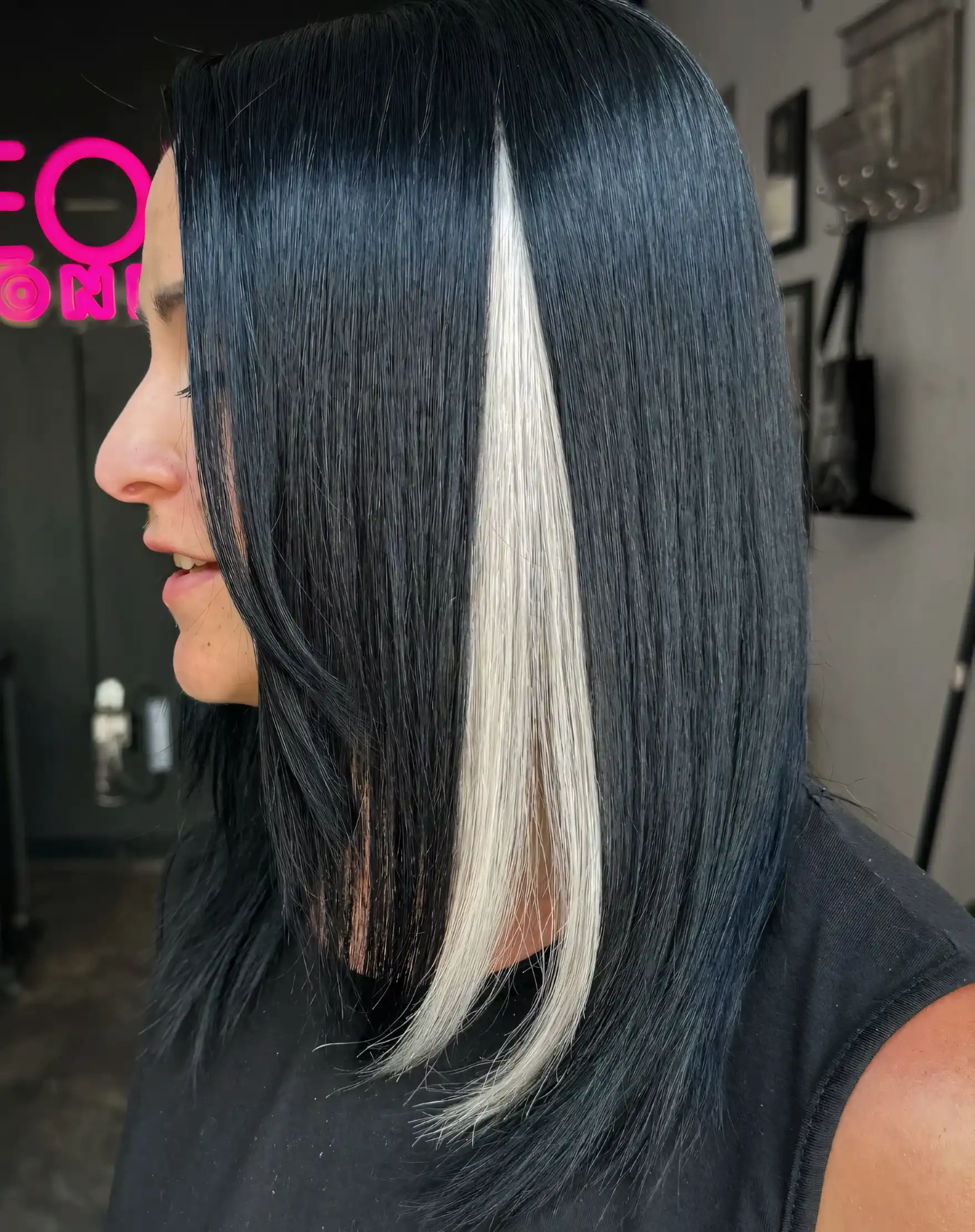 Sleek black straight hair with a single bold white face framing streak