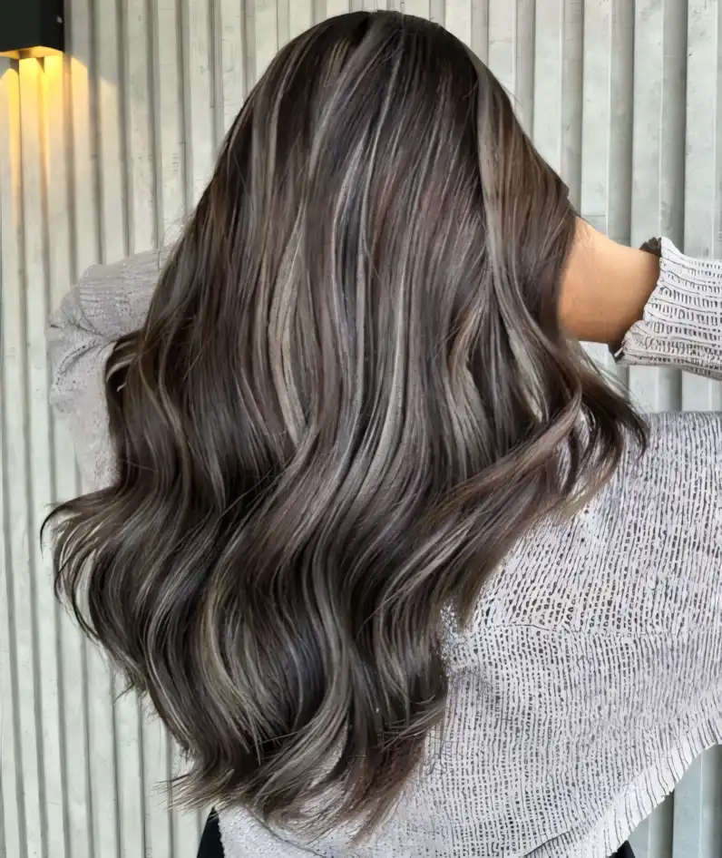 Long ash brown wavy hair blended with cool silver highlights