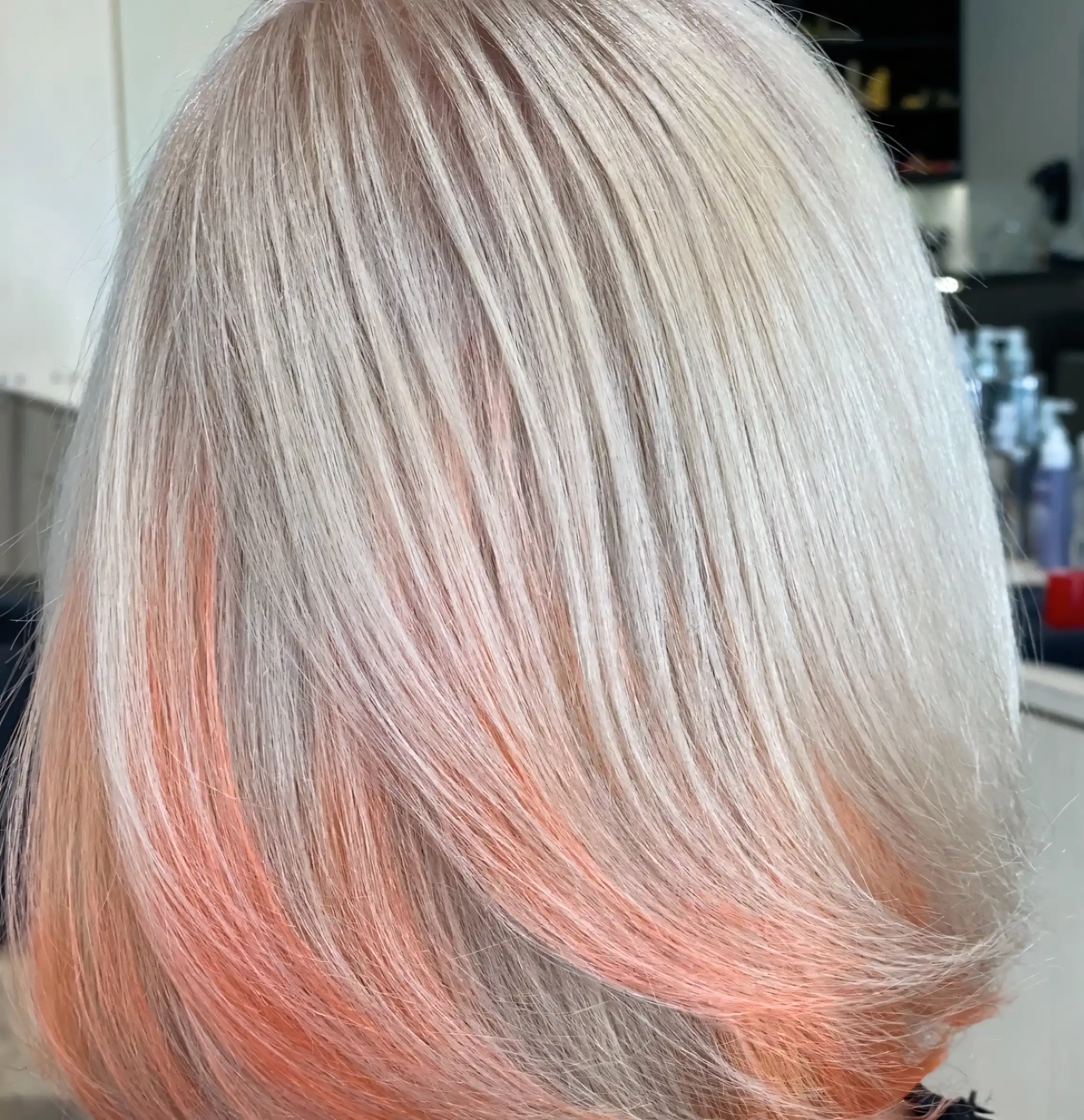 Pale platinum blonde hair with delicate coral pink highlights